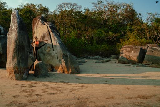 A young slim attractive Caucasian woman on a huge rock doing stretching exercises in nature on a sunny day