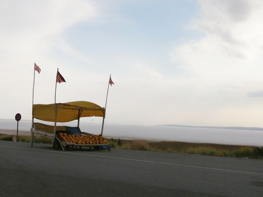 A closeup shot of fruits set up on a big wooden box on the highway for sale near the sea