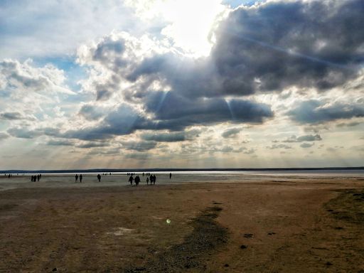A closeup shot of people on the beach under beautiful bright sunlight and partly cloudy sky