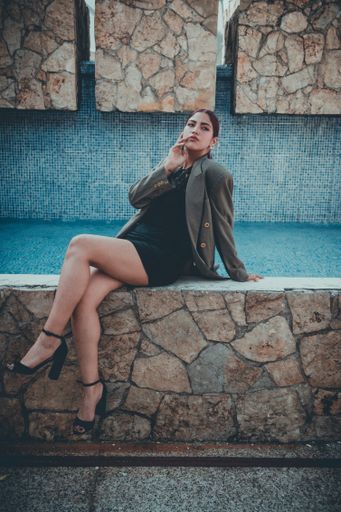 A vertical shot of an attractive redhead Hispanic lady from Ecuador posing sitting on a wall