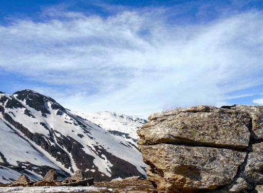 A rock with a background of snow-covered mountains