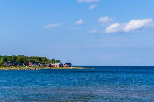 A scenic view of the red colored cottages near the sea on a sunny day