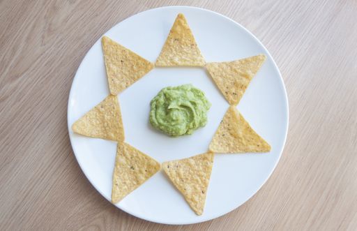 A beautiful shot of potato chips on a plate with homemade salsa Verde sauce