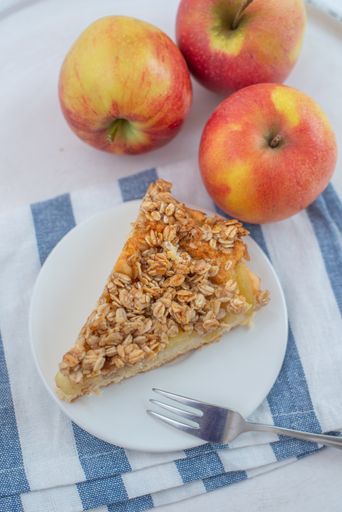 A vertical shot of a slice of apple cinnamon pie with oatmeal on a plate on the table