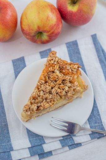 A vertical shot of a slice of apple cinnamon pie with oatmeal on a plate on the table