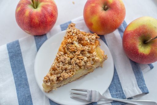 A high angle shot of a slice of apple cinnamon pie with oatmeal on a plate on the table