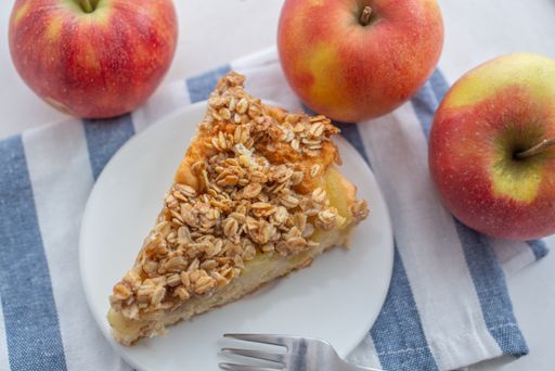 A high angle shot of a slice of apple cinnamon pie with oatmeal on a plate on the table