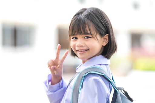 An adorable cute child schoolgirl posing with peace signs