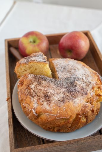A vertical shot of a delicious apple pie with sugar powder on a plate on a tray