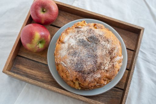 A top view of a delicious apple pie with sugar powder on a plate on a tray