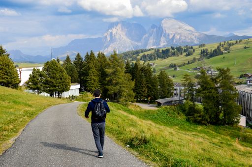 The man walking along the rural road. Alpe di Siusi, Dolomites, Italy.