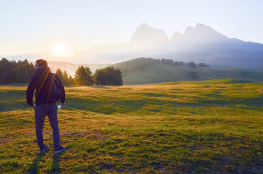 The man standing in the field against the background of the beautiful Dolomite Mountains. Italy.