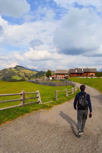 A vertical shot of the man walking along the rural road. Alpe di Siusi, Dolomites, Italy.