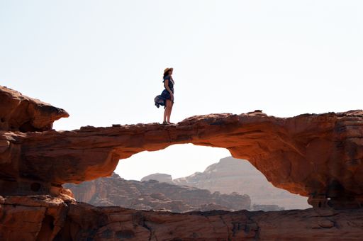 The beautiful view of the woman standing on a natural stone bridge. Wadi Rum, Jordan.