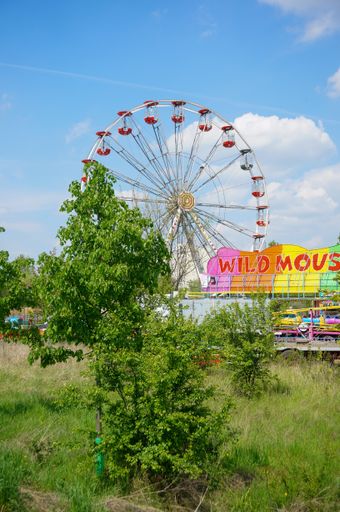 A vertical shot of the Ferris wheel against a blue cloudy sky at Rataje amusement park on a sunny day