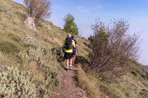 Two male hikers walking along a mountain path on a sunny day
