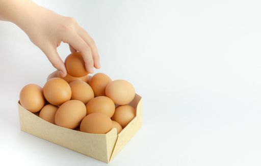 A box of frsh eggs isolated on a white background and a hand holding it