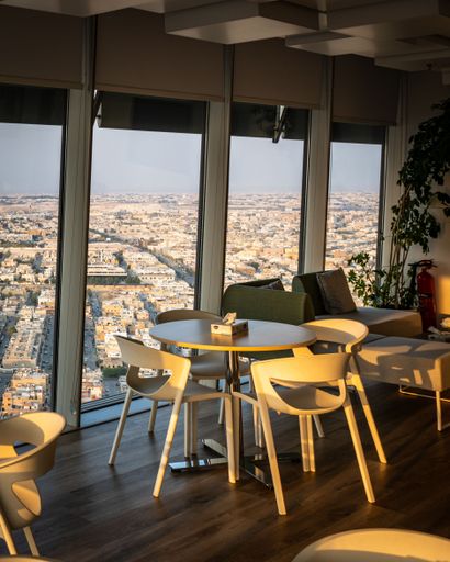 Modern interior with cityscape view from a high-rise building in Riyadh, featuring stylish furniture and large windows.