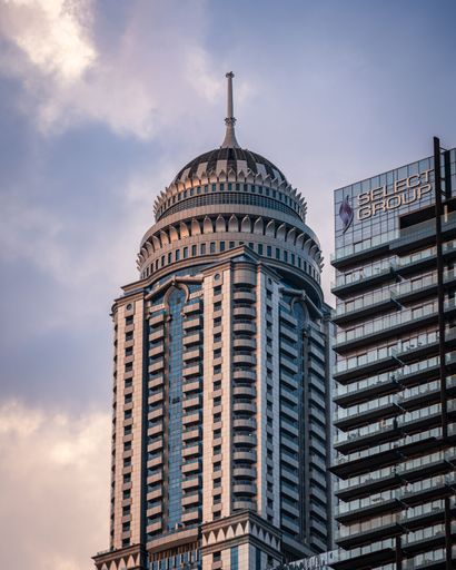 Close-up of a modern skyscraper with a unique architectural design against a cloudy sky in Dubai.