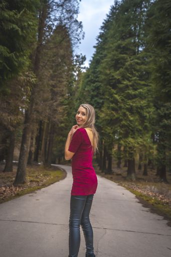 A vertical shot of a woman standing on a walkway in the park in Spain