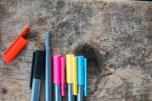 A closeup shot of colorful ball-point pens on a gray marble stone surface