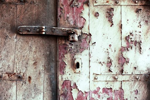 A closeup shot of a rusty door lock with bolt-on weathered wooden door in Europe