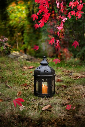 A black lantern with a lit candle in the garden in autumn