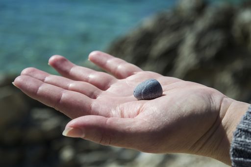A closeup shot of a person holding a piece of rock on a blurred background