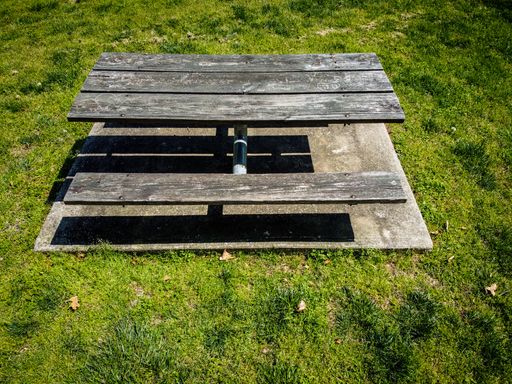A wooden picnic table on a cement slab in the park