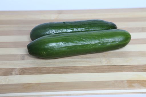 A closeup of ripe cucumbers on a wooden cutting board on the table