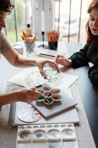 A vertical shot of two Caucasian females sitting together and painting