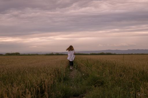 A shot of a Hispanic woman running in a field under the gloomy sky during sunrise in Spain