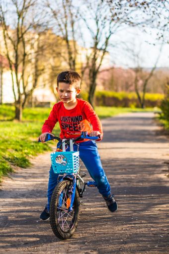 Young boy riding a bicycle on a footpath on a sunny day in the spring season.