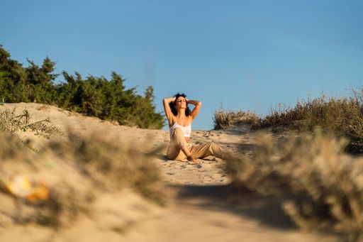 A vertical shot of a Spanish curly female posing on the sand