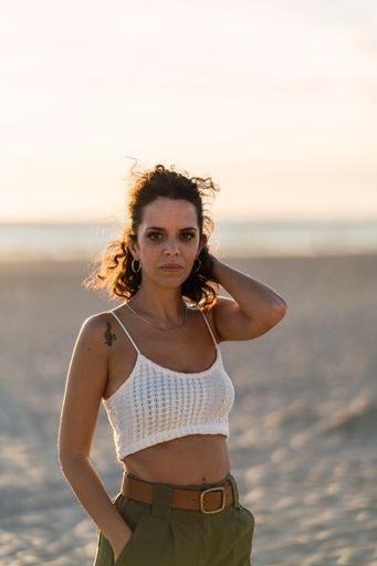 A vertical shot of a Spanish curly female posing on the sand