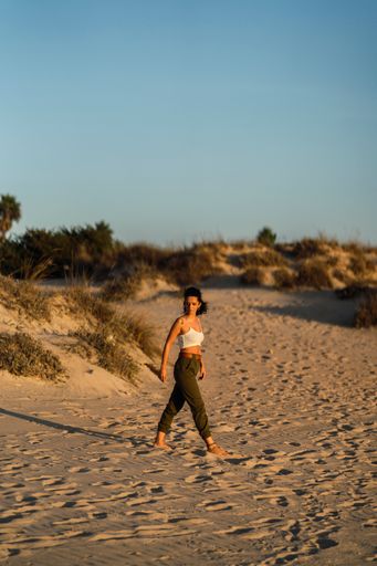 A vertical shot of a Spanish curly female posing on the sand