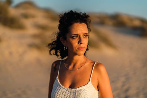 A vertical shot of a Spanish curly female posing on the sand