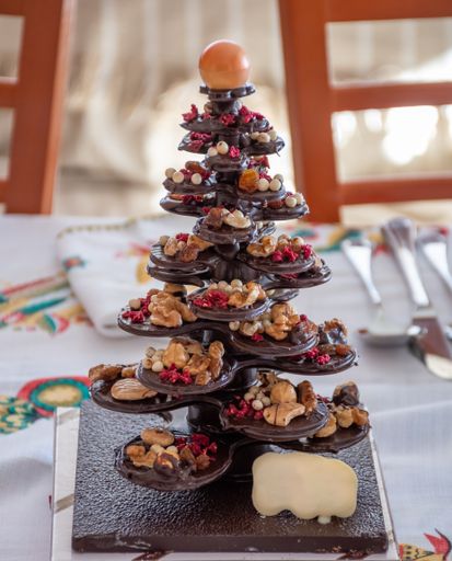 A decorative dark chocolate Christmas tree with nuts and a white chocolate sign for copy space