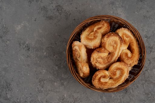 A top view of a basket with puff pastry palmeritas, also known as orejitas (little ears)