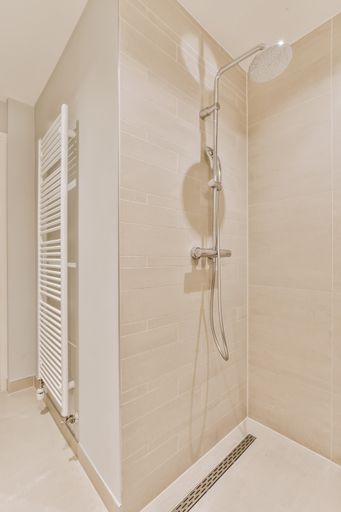 A beautiful vertical image of a bathroom shower area in a white interior design house; design ide
