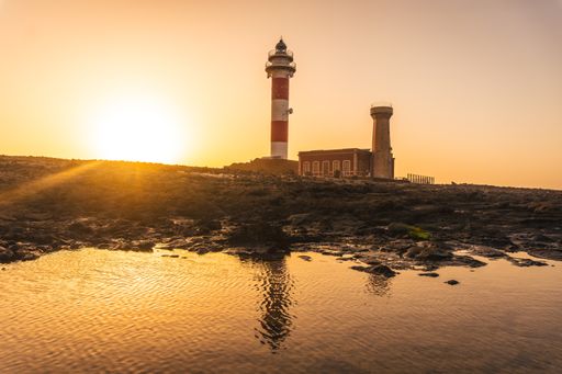 A beautiful view of the Toston Lighthouse with its reflection in the water at sunset in Punta Ballena, Fuerteventura, Canary Islands, Spain