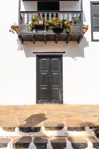 A vertical shot of a portal of the municipality of Betancuria with an adorable black balcony full of flowers, Spain
