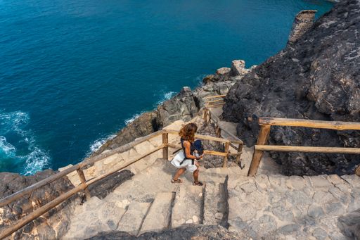 A young Caucasian female on the stairs of the path of the Cuevas de Ajuy, Pajara, west coast of the island Fuerteventura, Canary Islands, Spain