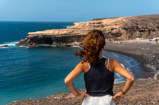 A Caucasian female standing and looking at the sea on the beach of Ajuy, Pajara, west coast of the island Fuerteventura, Canary Islands, Spain