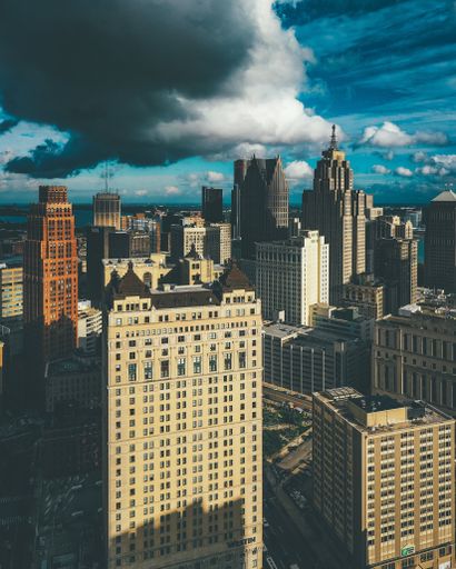 A vertical picture of buildings under a cloudy sky and sunlight in Detroit in Michigan, the USA