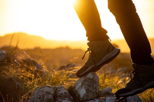 Silhouette of a hiker's boots on rocky terrain at sunset, capturing the essence of outdoor adventure.