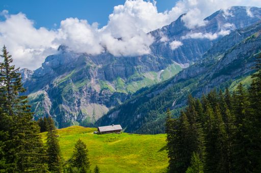An aerial view of the rocky green mountains under the cloudy blue sky