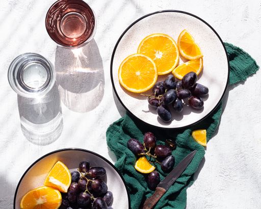 A top view of sliced oranges and grapes on plates on the table.