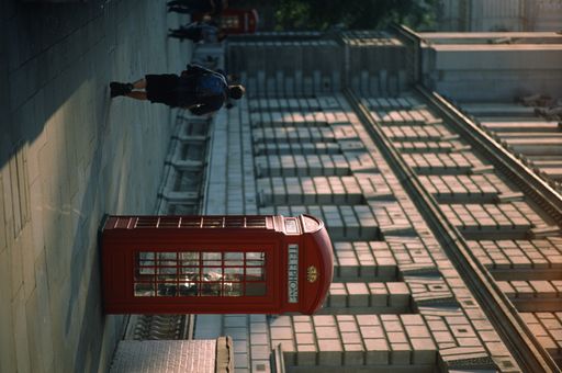 A vertical shot of red phone booths on the sidewalks of the city