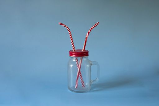 A closeup shot of two straws in a cup isolated on a blue background